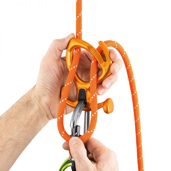A person holding a PIRANA climbing carabiner and a carabiner.