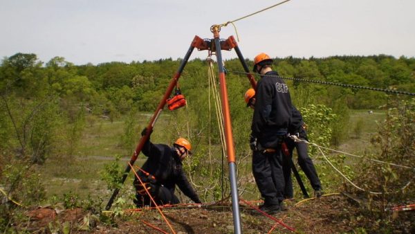 A group of men are working with the TerrAdaptor Portable Anchor System in the woods.