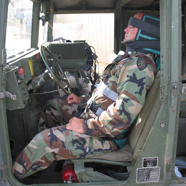 A man is sitting in the driver's seat of an OREGON SPINE SPLINT II – Coyote Brown military vehicle.