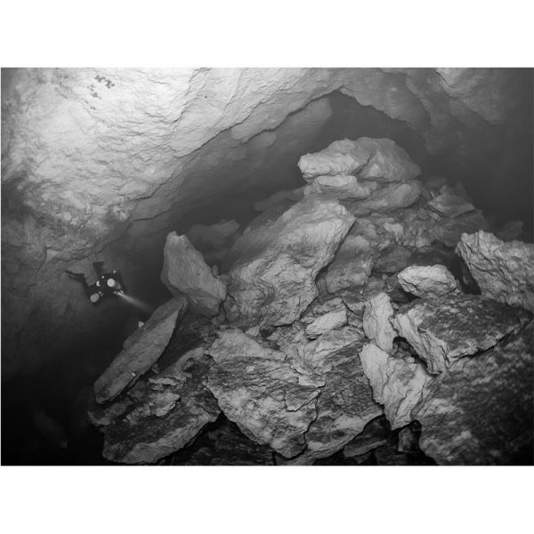 A black and white photo of a person wearing SLIPSTREAM MONOPRENE FINS in a cave.