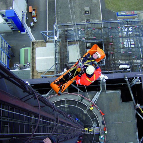 A man is climbing a Sked® Basic Rescue System – International Orange.