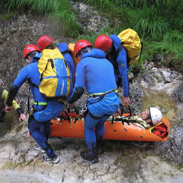 A group of people on a Sked® Basic Rescue System – International Orange in a river.