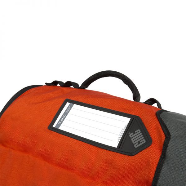 An orange and black FIELD GUIDE bag with a tag on it.