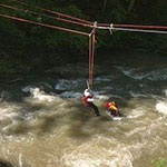 A group of people on a zip line in a river.